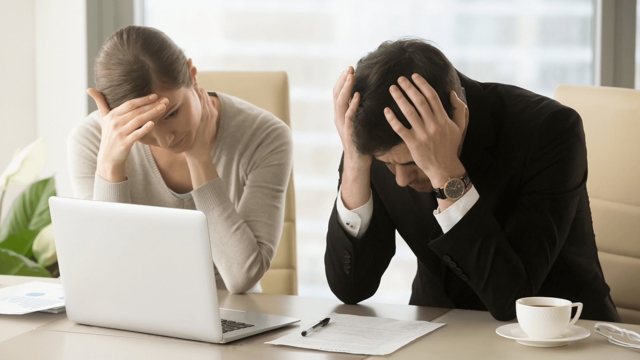 Woman and man cringing in front of laptop